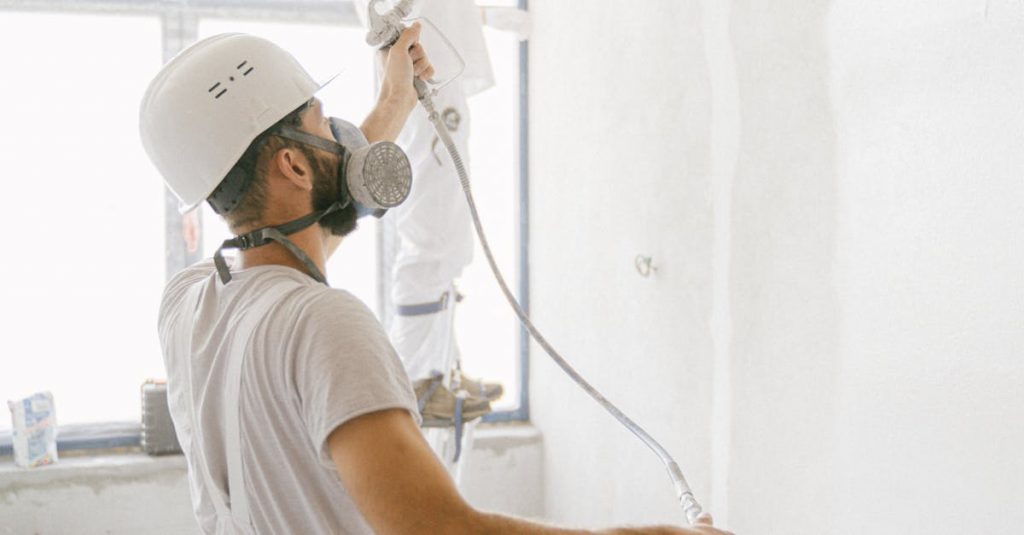 Two professional painters working indoors on wall renovation and painting project.